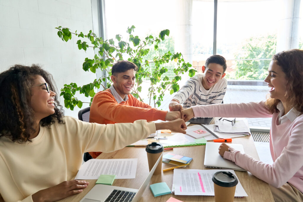 A group of Gen Z employees giving fist bump to celebrate direct sales success.